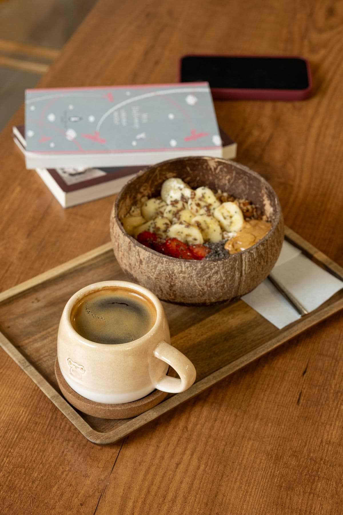 A smoothie bowl and coffee on a wooden tray.