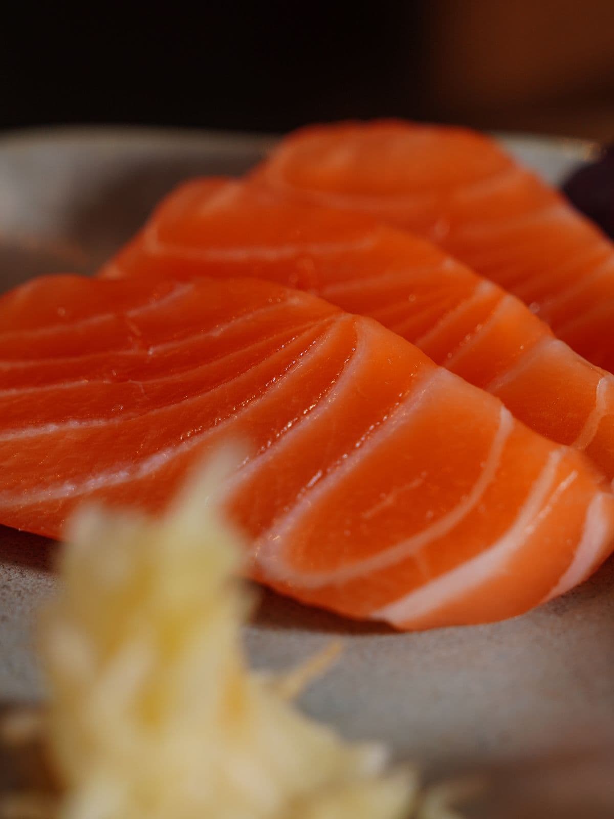 Fresh salmon sashimi on a ceramic plate.