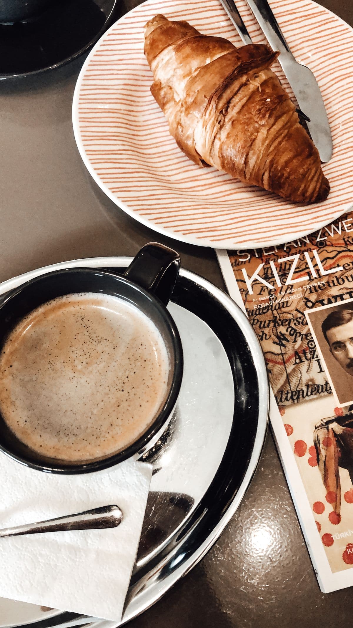 A croissant and coffee on a café table.