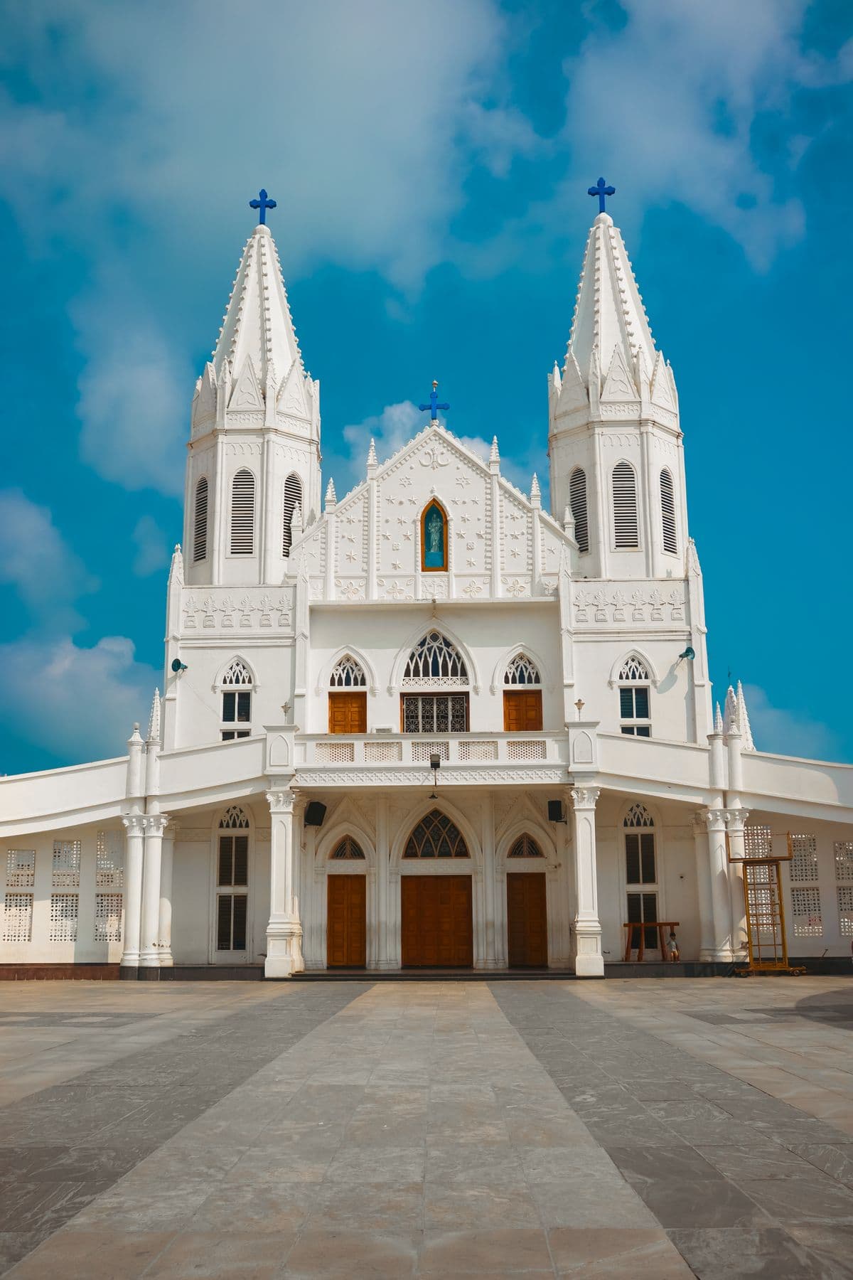 A whitewashed twin-towered Goan church against a blue sky.