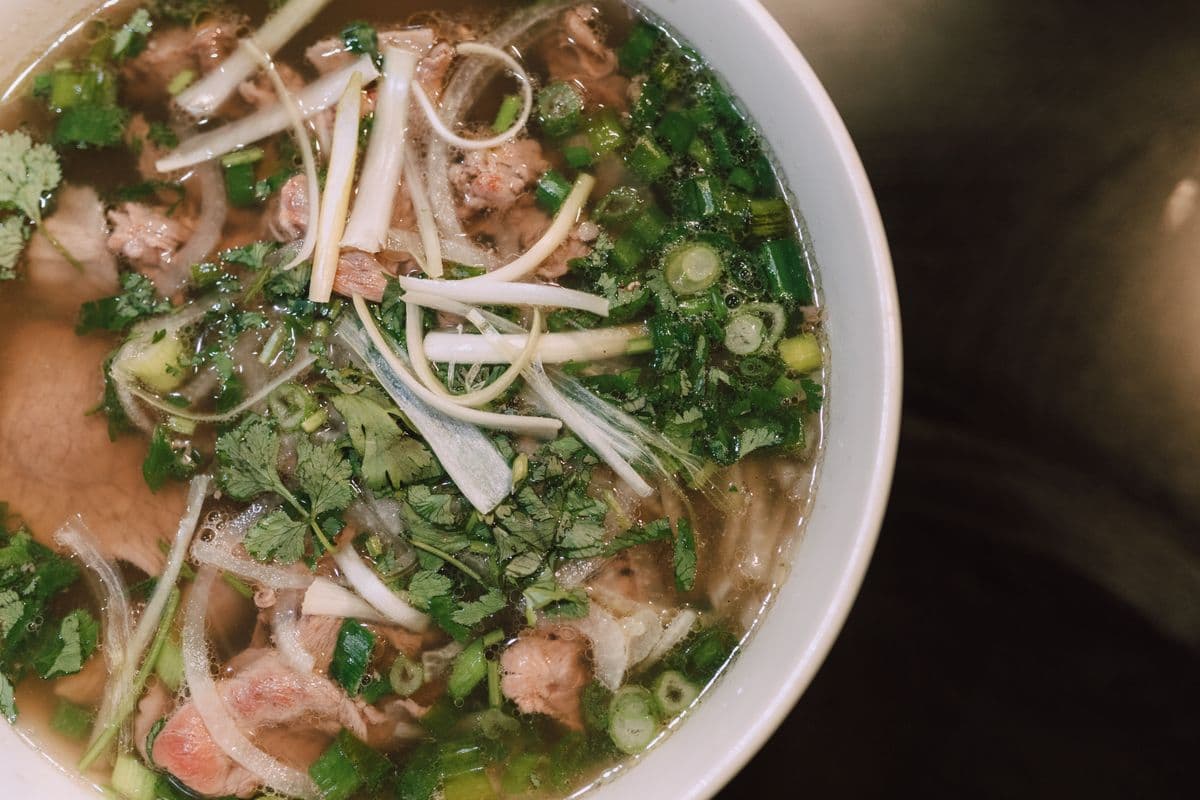 A close-up of a herb-topped bowl of Vietnamese pho.