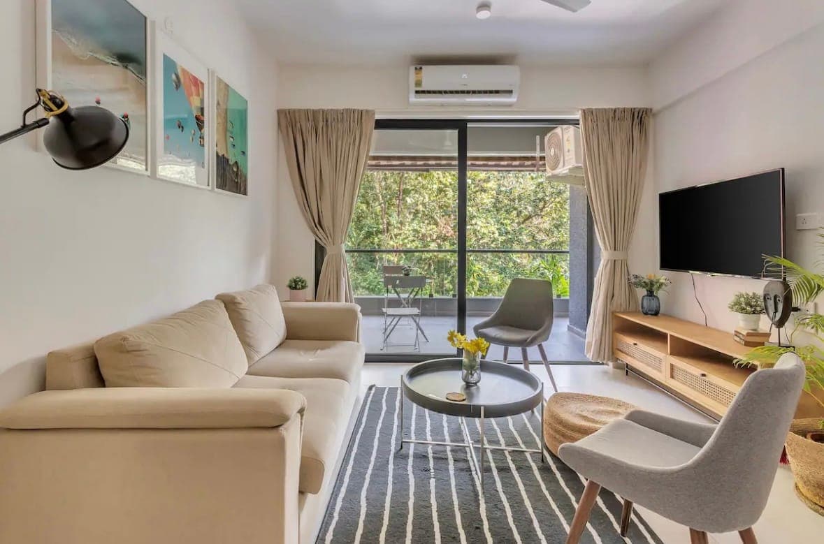 The living room with a television and balcony doors.