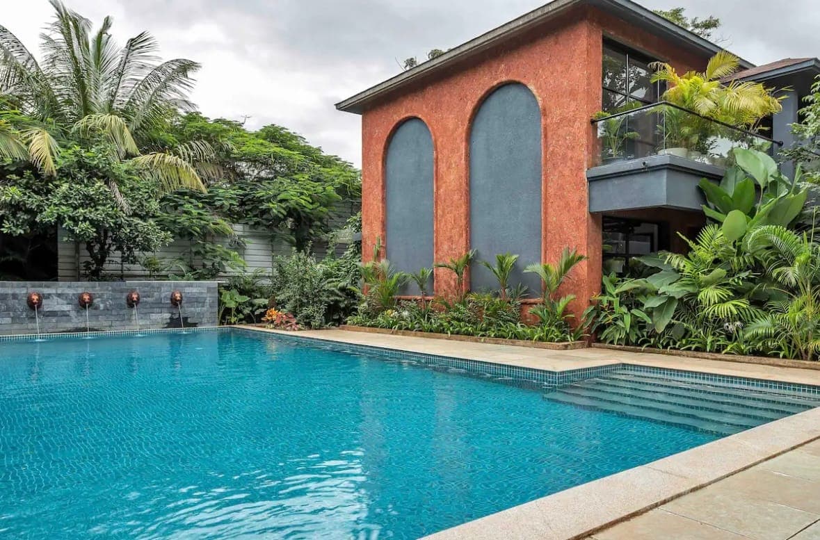 The pool beside a Nistula Assagao apartment, framed by palms and an arched garden wall.